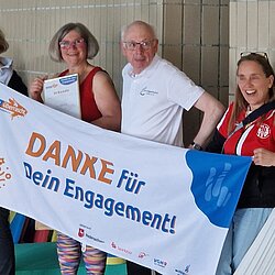 Vier Personen halten ein Banner mit der Aufschrift „DANKE für Dein Engagement!“, eine Frau zeigt eine Urkunde.