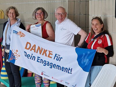 Vier Personen halten ein Banner mit der Aufschrift „DANKE für Dein Engagement!“, eine Frau zeigt eine Urkunde.
